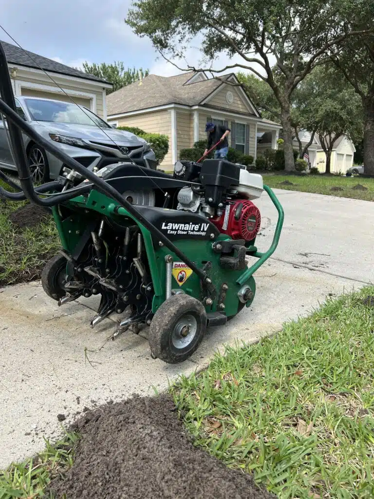 Core aerator in the foreground and lawn being prepped for the service in the background